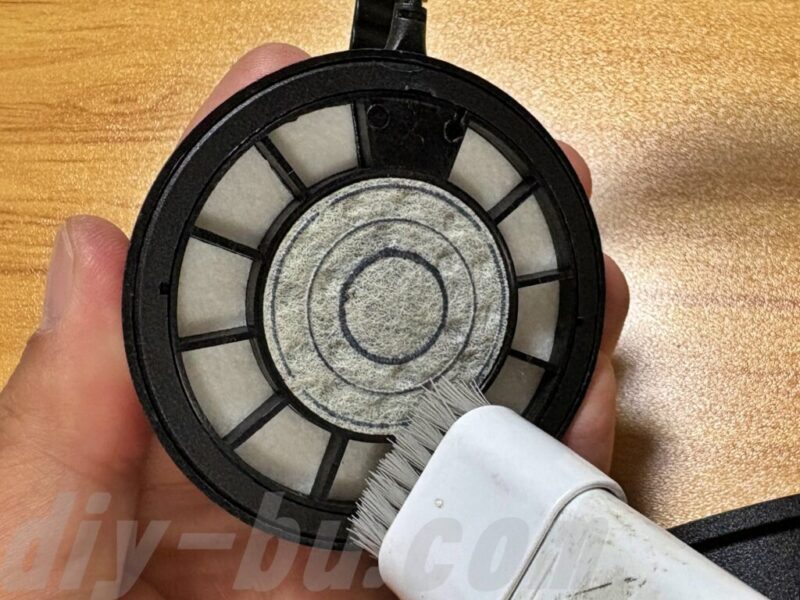 イヤーパッドを外した後のヘッドホンをハンディ掃除機で掃除している様子